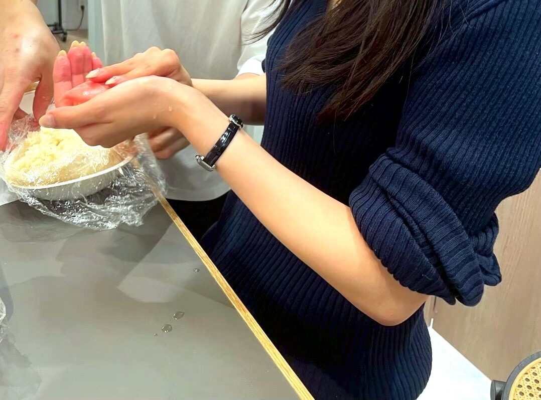 A guest's hand receiving a piece of nigiri from the chef